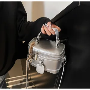 Detail view of a silver mirror-finish box bag with top handle and metal hardware