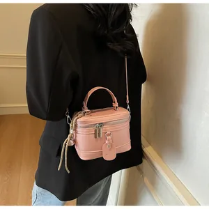 Pink minimalist bucket bag shown over shoulder with dual zippers and woven detail