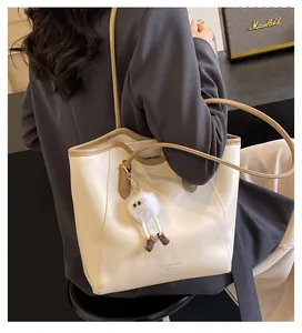 Detail view of contrast stitch tote bag featuring plush charm and Fashion Trend print