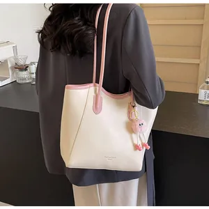 Detail of cream and pink tote bag with plush monster charm in a cafe setting
