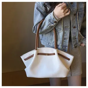 Detail der weißen Tragetasche aus strukturiertem Leder mit braunen Riemen und Goldbeschlägen