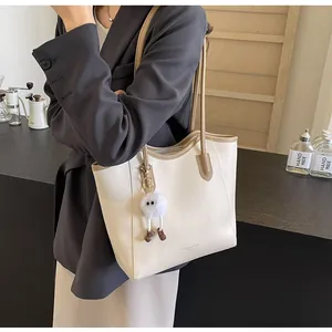Detail of cream and khaki tote bag with plush charm on a coffee bar background