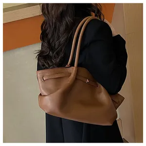 Seitenansicht einer großen braunen Leder-Tote-Bag mit dekorativen Kordelzügen am Model