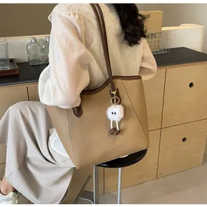 Detail view of large brown faux leather tote bag with stylish plush pendant and logo