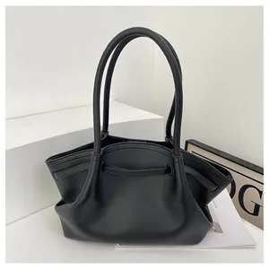 Detail der schwarzen Handtasche aus Leder mit moderner Trapezform und feiner Faltentextur