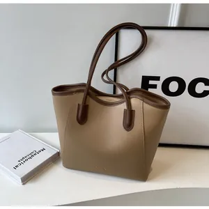 Detail of color-block tote bag with khaki body and dark brown handles for work