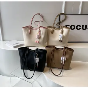 Detail view of four minimalist tote bags in neutral colors with plush doll pendants