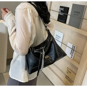 Κοντινό πλάνο της μαύρης γυαλιστερής τσάντας tote με κομψή ασημένια μεταλλική αλυσίδα