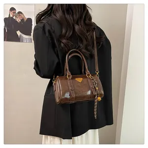Detail of dark brown vintage bowling bag showing glossy leather texture and gold hardware