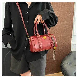 Detail of burgundy retro bowling bag with gold hardware and tassel charm accent