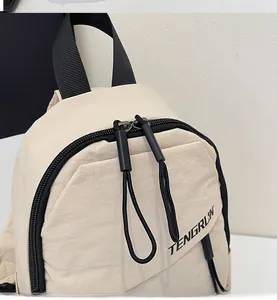 Detailansicht der beigen Nylontasche mit glattem schwarzem Doppelreißverschluss und Logo