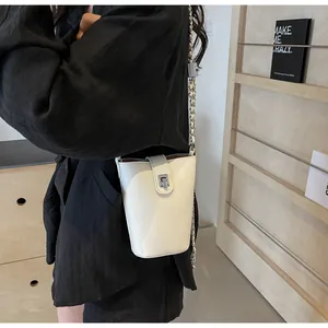 Close-up of white mini bucket bag with silver chain strap and metal buckle on model