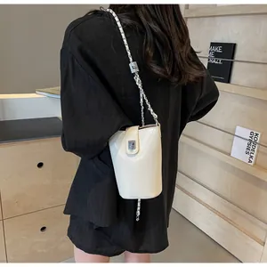 Back view of model wearing a stylish cream bucket bag with chain strap in a library
