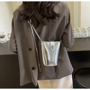Detail of trendy silver metallic bucket bag with chain strap shown in a lifestyle setting
