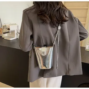 Detail of silver metallic bucket bag showing T-shaped metal clasp and chain strap