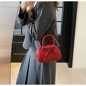 Detail of red bow mini handbag worn over the shoulder with a stylish grey suit