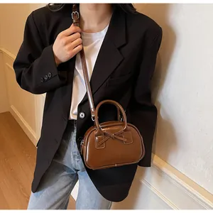 Brown bow handbag in glossy retro style shown by model with shoulder strap usage