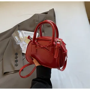 Detail of red patent leather handbag with bow design and adjustable strap