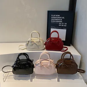 Minimalist handbag with bow design in five colors featuring smooth PU leather and silver strap