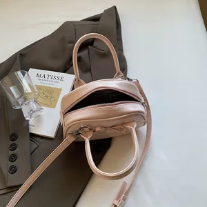 Pink faux leather handbag with bow detail and adjustable strap for women