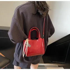 Dettaglio borsa a secchiello in pelle rossa lucida con logo XICH XICH in rilievo