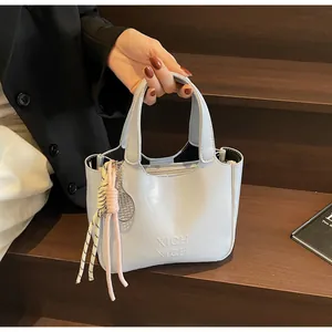 Dettaglio borsa a secchiello azzurra con logo a rilievo e ciondolo racchetta da tennis