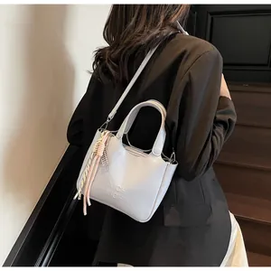Dettaglio della borsa a secchiello grigio chiaro con logo e ciondolo a nappa intrecciata