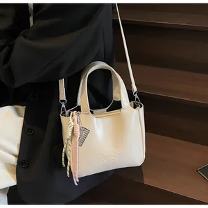 Dettaglio borsa a secchiello off-white con goffratura XICH XICH e ciondoli in corda