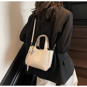 Dettaglio borsa a secchiello in pelle crema con logo XICH XICH e foulard sul manico