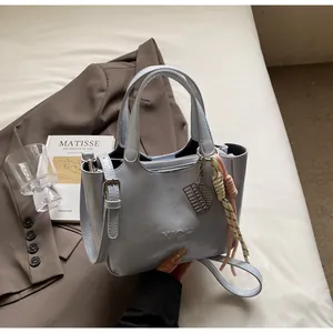 Dettaglio borsa a secchiello azzurra con logo XICH e corda intrecciata su un blazer