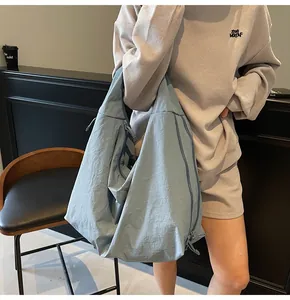 Detail of light blue slouchy canvas tote bag showing drawstring and functional zipper