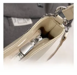 Close-up of high-quality silver metal zipper and stitching on cream faux leather bag