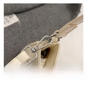 Close-up of premium silver metal hook and smooth cream leather on shoulder bag