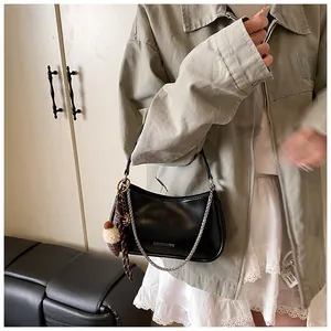 Detail of black leather baguette bag with silver chain and cute plush ice cream charm
