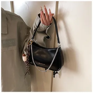 Detail of black leather underarm bag featuring silver chain and cute plush ice cream charm