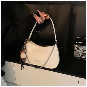 Detail of cream white underarm bag with silver chain and brand logo on shiny PU leather