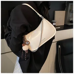 Detail of cream leather underarm bag featuring silver chain and cute ice cream charm