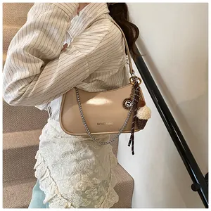 Detail of beige shoulder bag with silver chain strap and plush ice cream charm pendant