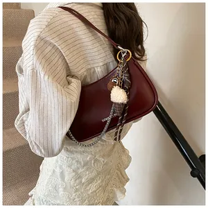 Detail of wine red shoulder bag with metallic chain and ice cream charm on model