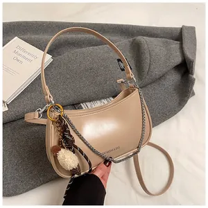 Detail of beige crescent underarm bag on a wool coat with chain and plush charm