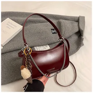 Detail of burgundy glossy hobo bag with silver chain and cute ice cream charm accessory