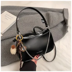 Detail of black leather underarm bag with silver chain and white plush sheep charm