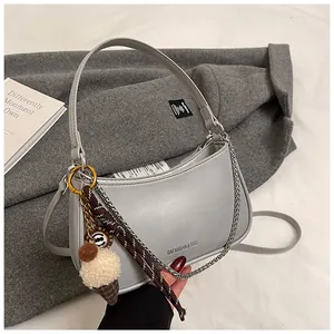 Detail of silver crescent shoulder bag with chain strap and plush ice cream charm