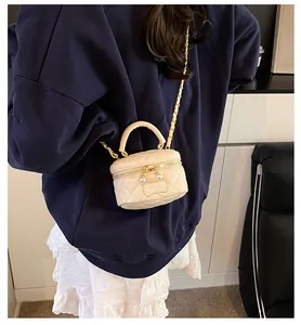 Close-up of beige quilted mini bag with gold chain and dual pearl zipper accents