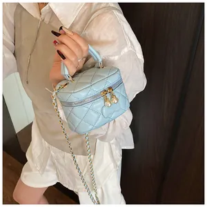Detail of light blue quilted mini bag with pearl charm and gold chain strap
