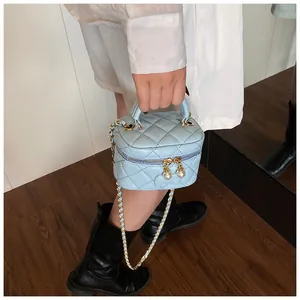 Close-up of light blue quilted mini bag featuring elegant pearl zipper charms and chain strap