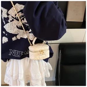 Detailed view of cream quilted mini cylinder bag with pearl zippers on a model