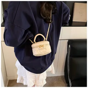 Detail of cream quilted leather mini bag featuring pearl zippers and woven chain strap