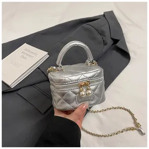 Detail of silver quilted mini bag with pearl zippers and golden chain strap
