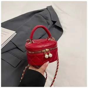 Detail of red quilted mini bag with dual pearl charms on zipper and gold chain strap